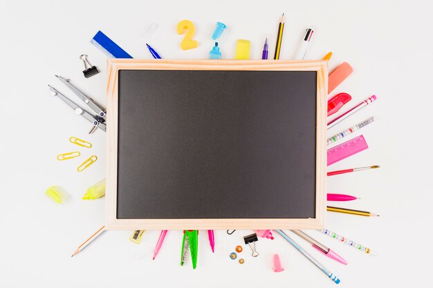 Bright school supplies set around chalkboard