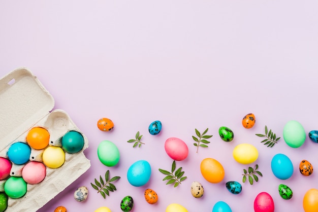 Bright set of colored eggs near container and leaves