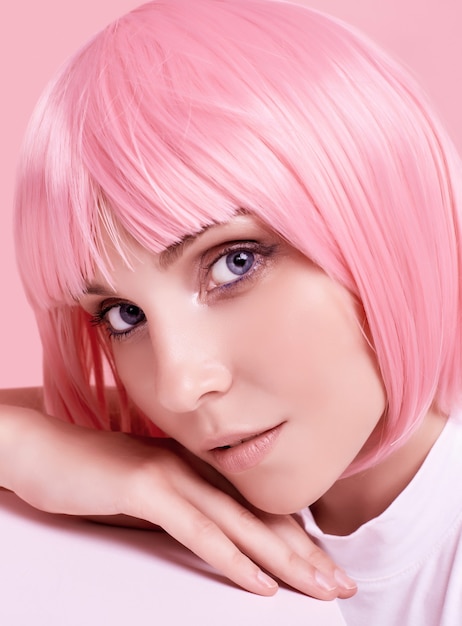 Bright summer portrait of a positive, gorgeous girl with pink hair posing on studio colorful