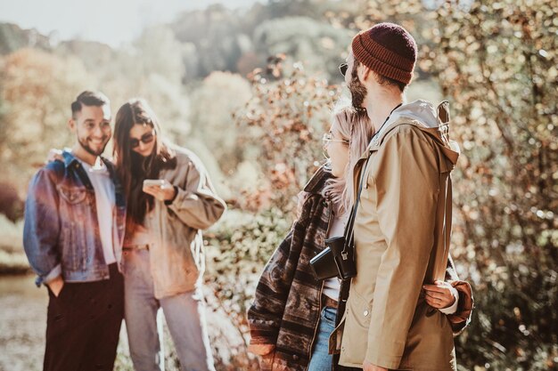 In the bright sunny day group of friends are enjoying their walk at autumn forest.