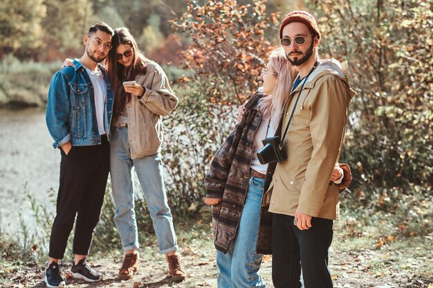 In the bright sunny day group of friends are enjoying their walk at autumn forest.