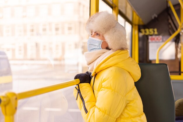 Bright sunny portrait of a young woman in warm clothes in a city bus on a winter day