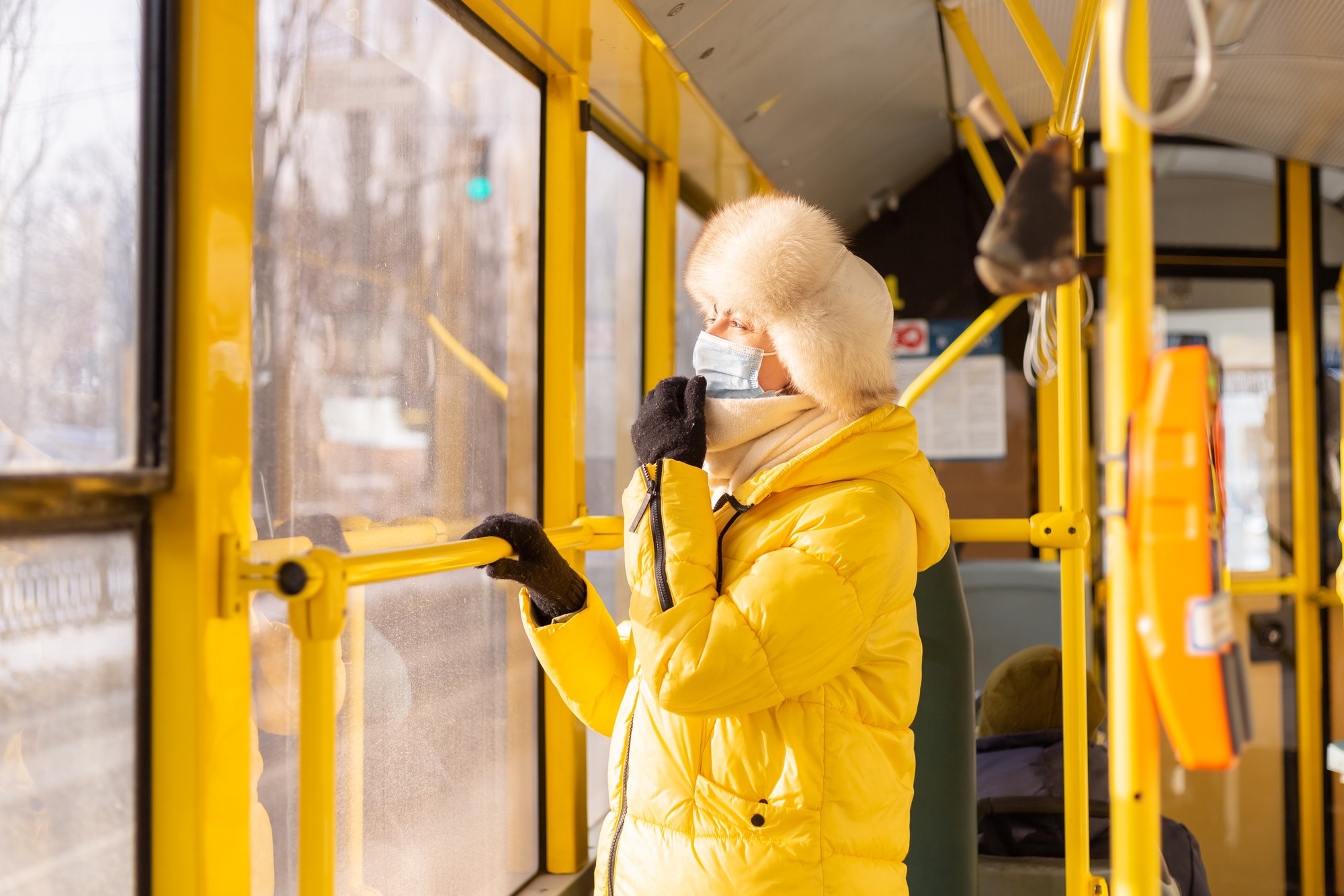 冬の日の市バスで暖かい服を着た若い女性の明るく日当たりの良い肖像画