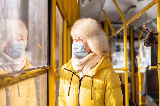 Bright sunny portrait of a young woman in warm clothes in a city bus on a winter day