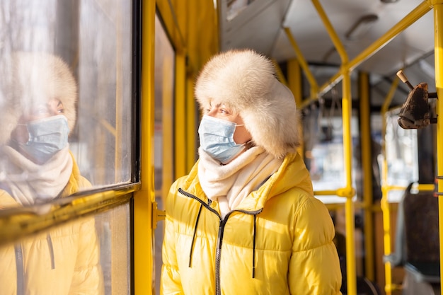 冬の日の市バスで暖かい服を着た若い女性の明るく日当たりの良い肖像画