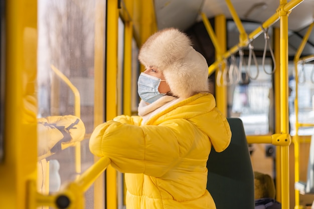 Яркий солнечный портрет молодой женщины в теплой одежде в городском автобусе в зимний день