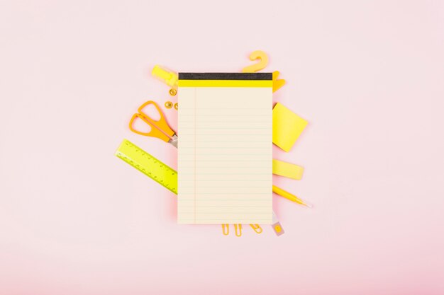 Bright yellow office supplies behind empty notepad