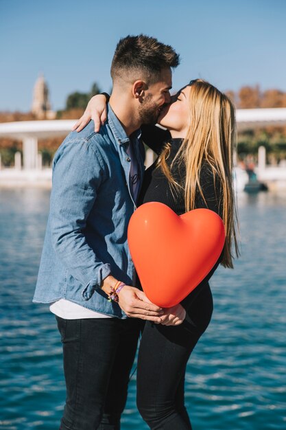 Bright young couple kissing romantically on waterfront