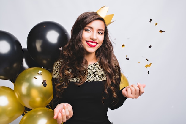 Brightful party of joyful young woman in elegant  fashion black dress and yellow crown celebrating new year,