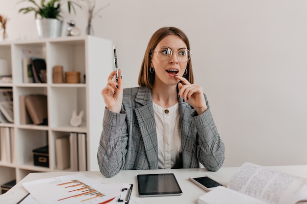 Brilliant idea came to mind of young business woman in stylish jacket and glasses sitting in workplace.