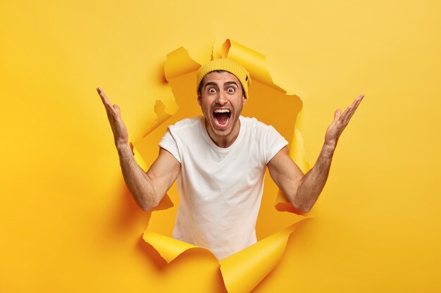 Brilliant! Optimistic overjoyed unshaven European man raises hands, impressed by something awesome