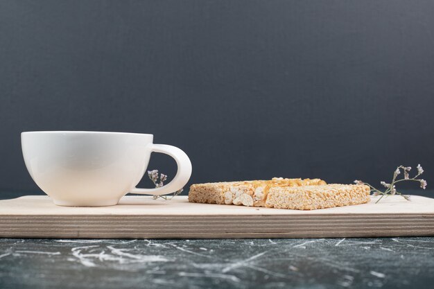 Brittle candies and cup of tea on wooden board. High quality photo