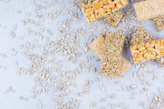 Brittle candies with seeds and peanuts on marble background. 