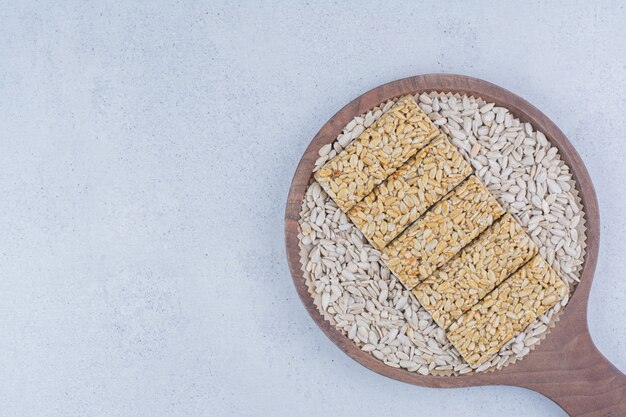 Brittle candies with sunflower seeds on cutting board. 