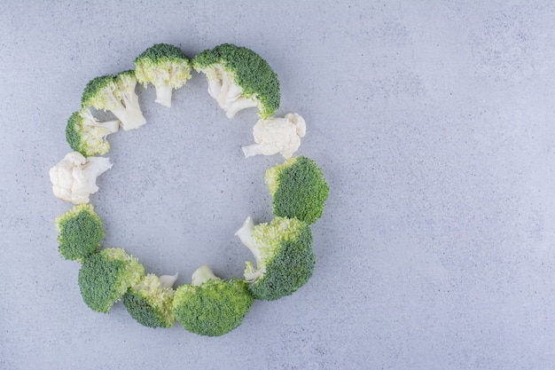 Broccoli arranged in a ring on marble background.