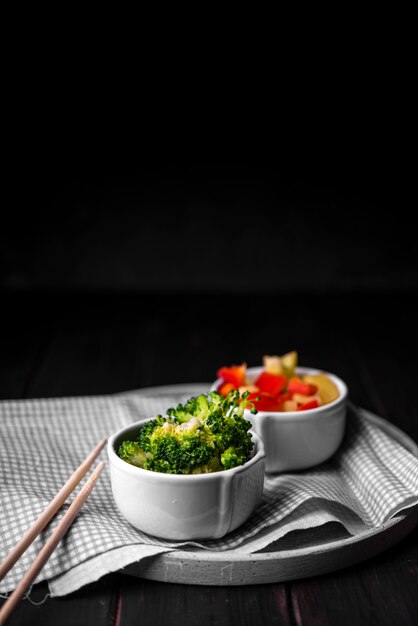Broccoli in cup with chopsticks and bell pepper