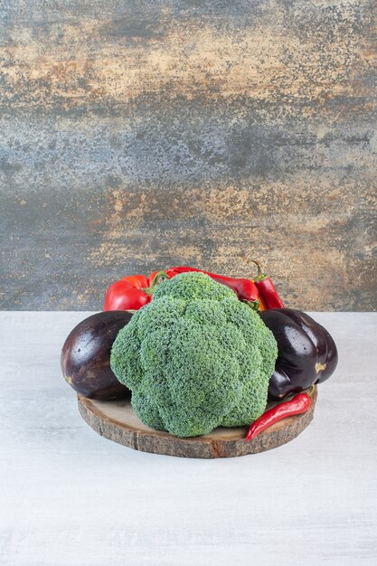 Broccoli, eggplants and peppers on wooden piece. High quality photo