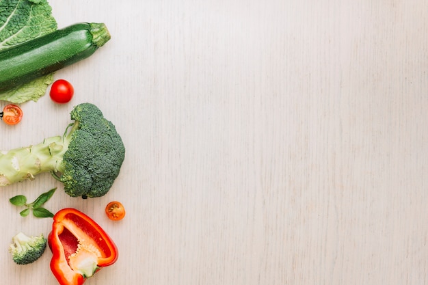 Broccoli; halved bell pepper; cherry tomatoes and zucchini on cream wooden surface