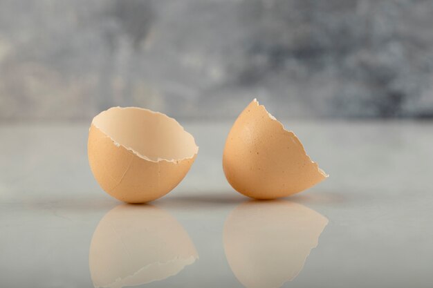 Broken brown eggshell on a marble surface. 