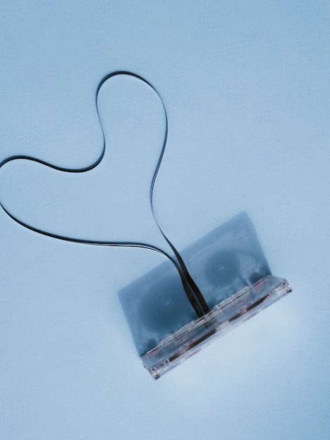 Бесплатное фото Сломанная кассета с формой сердца на синем фоне