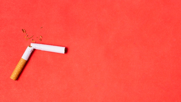 Broken cigarette on red background