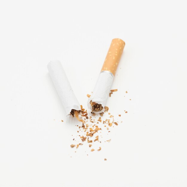 Сломанная сигарета и табак на белом фоне
