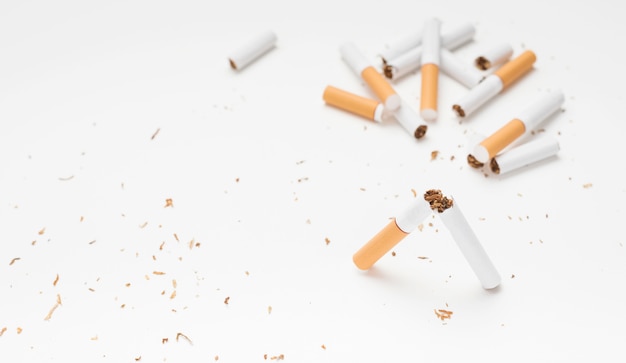 Broken cigarette and tobacco above white surface