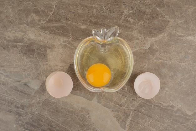 Broken egg on plate on marble table .