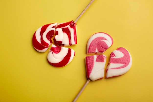 Broken heart shaped candy on yellow background