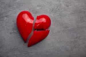 Free photo broken plastic red heart on grey background