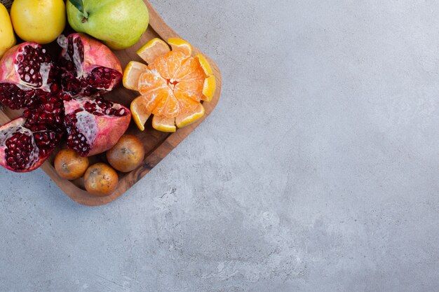 Broken pomegranate, peeled tangerine and whole quinces and pears on a piece of cloth on marble background. 