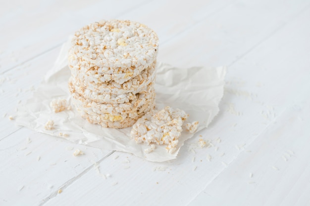 Broken and round puffed rice cakes on white wooden table