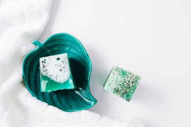 Broken soap in the leaf bowl with napkin on white background