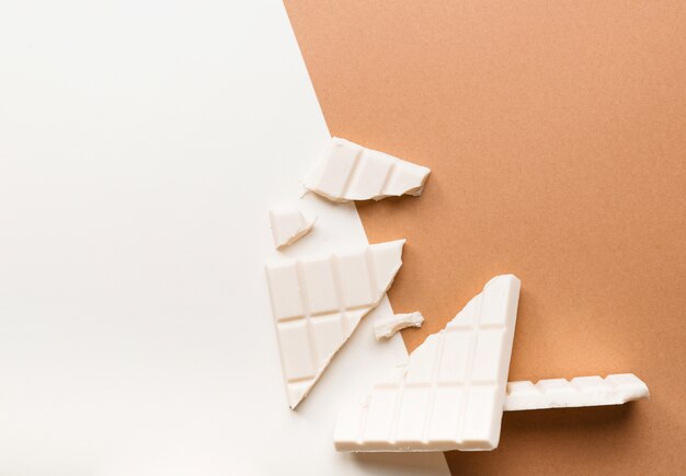 Broken white chocolate bar against dual colored background