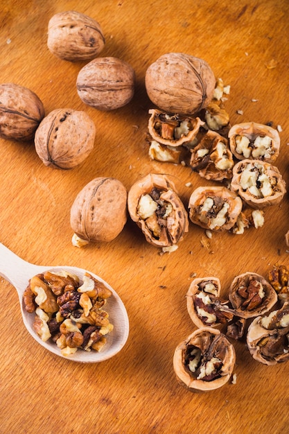 Broken and whole walnuts with kernel on wooden spoon