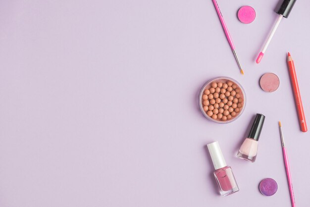 Bronzed pearls with cosmetics products on colored background