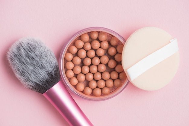 Bronzing pearls; sponge and makeup brush on pink backdrop