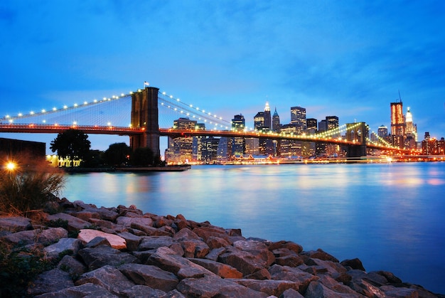 夜のハドソン川に架かるニューヨーク市のブルックリン橋とマンハッタンのスカイライン。