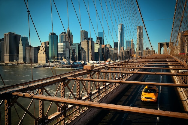 브루클린 다리(Brooklyn Bridge)는 노란색 택시와 고층 빌딩이 있는 맨해튼(Manhattan)을 볼 수 있습니다.