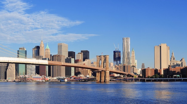 Foto gratuita il ponte di brooklyn con il panorama dello skyline di manhattan al mattino con nuvole e cielo blu sull'east river a new york city