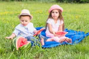 Бесплатное фото Брат и сестра, наслаждаясь арбузом в парке