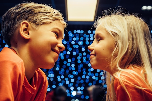 Free photo brother and sister on the background of a festive garland, new year lights, children.