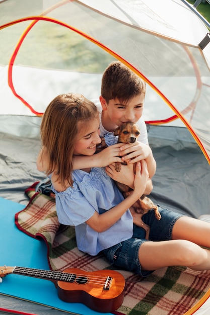 Brother and sister loving their pet sitting in tent