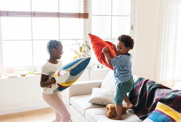 Brother and sister pillow fighting in living room