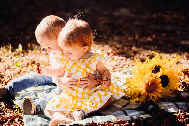 Brother and sister play on the blanket in sunny park 