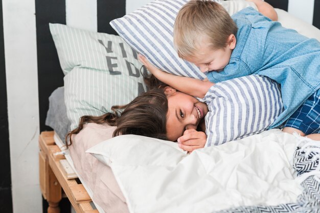 Brother and sister playing with pillows on bed