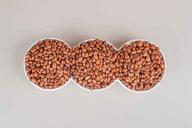 Free photo brown beans in a ceramic plate on concrete.