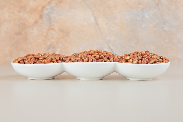 Brown beans isolated in a ceramic cup on concrete.