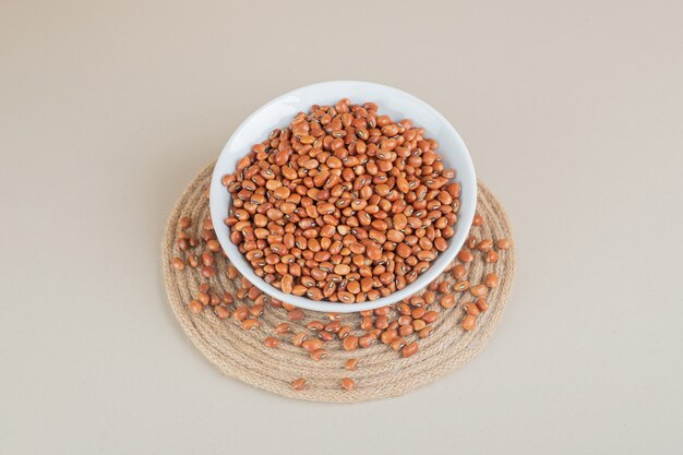 Brown beans isolated in a ceramic cup on concrete.