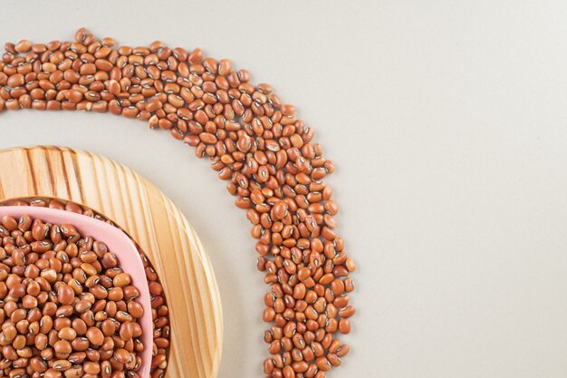 Brown beans in a yellow platter on concrete.